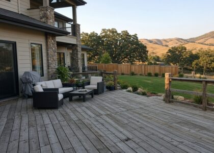Weathered gray wood deck with patio furniture behind a stone-accented home near the foothills